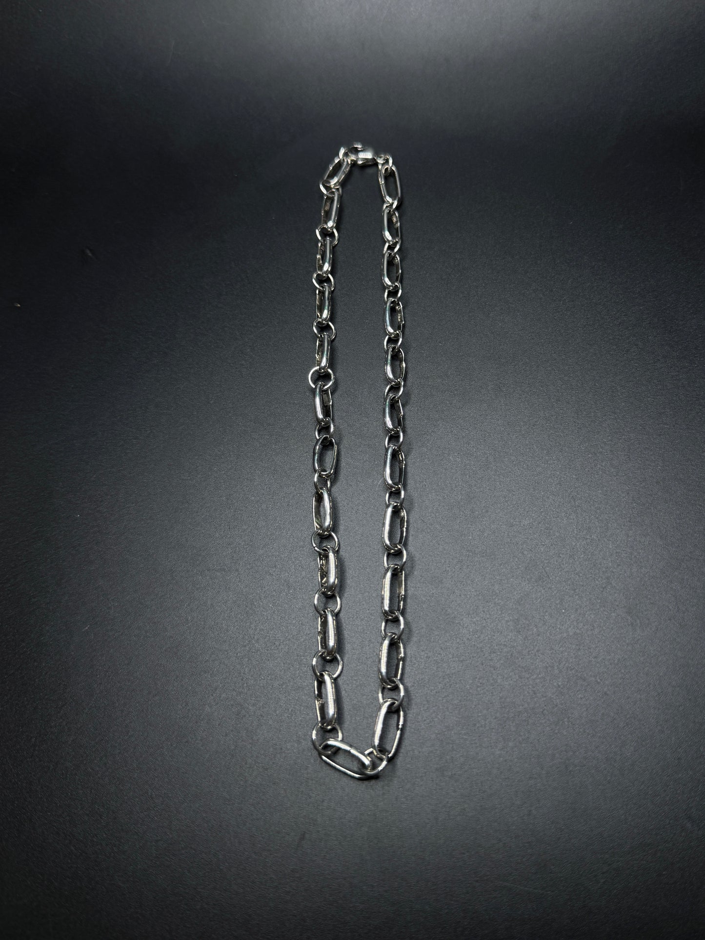 Silver chain necklace on a dark gray background