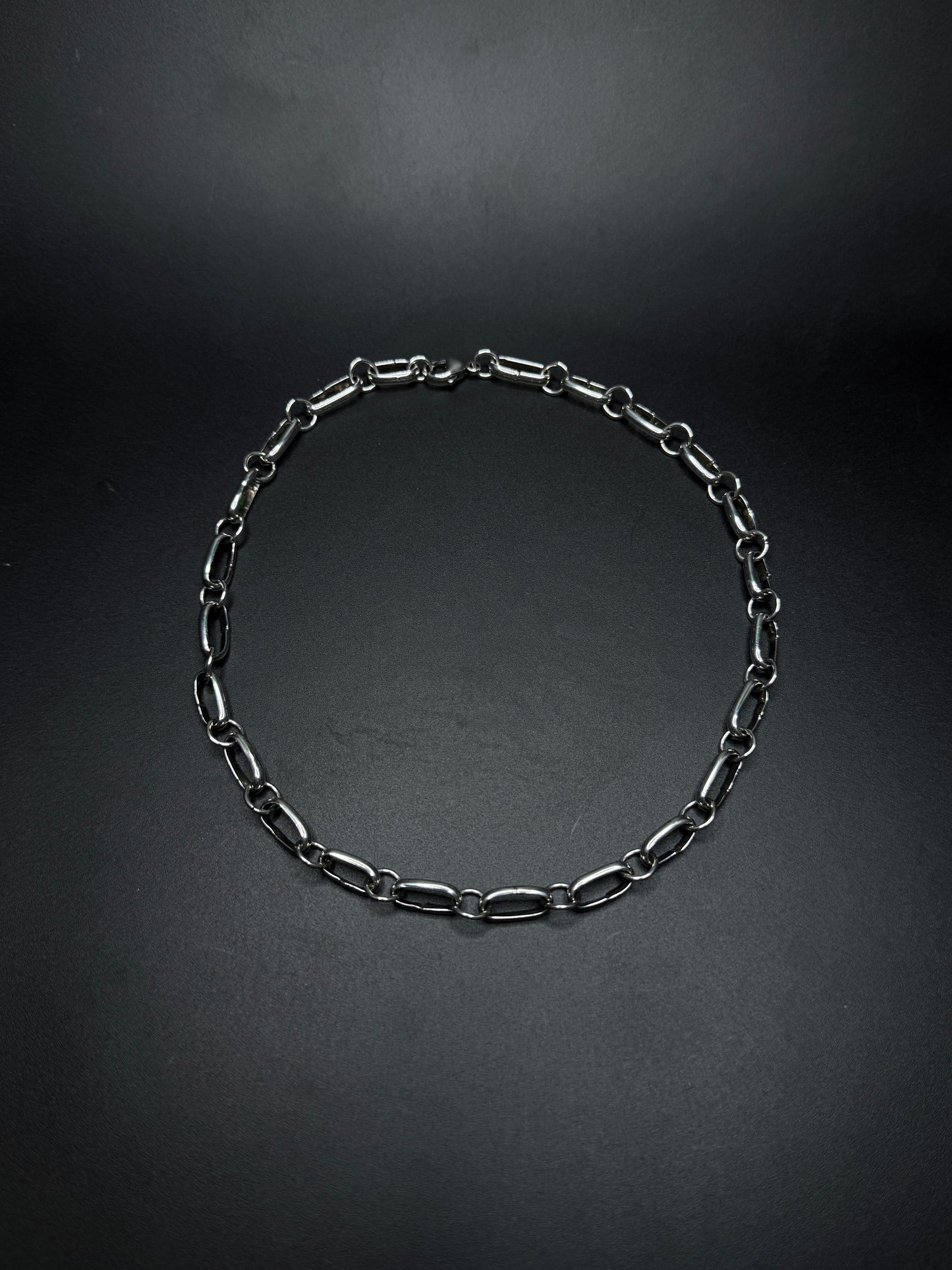 Black chain necklace on a dark gray background