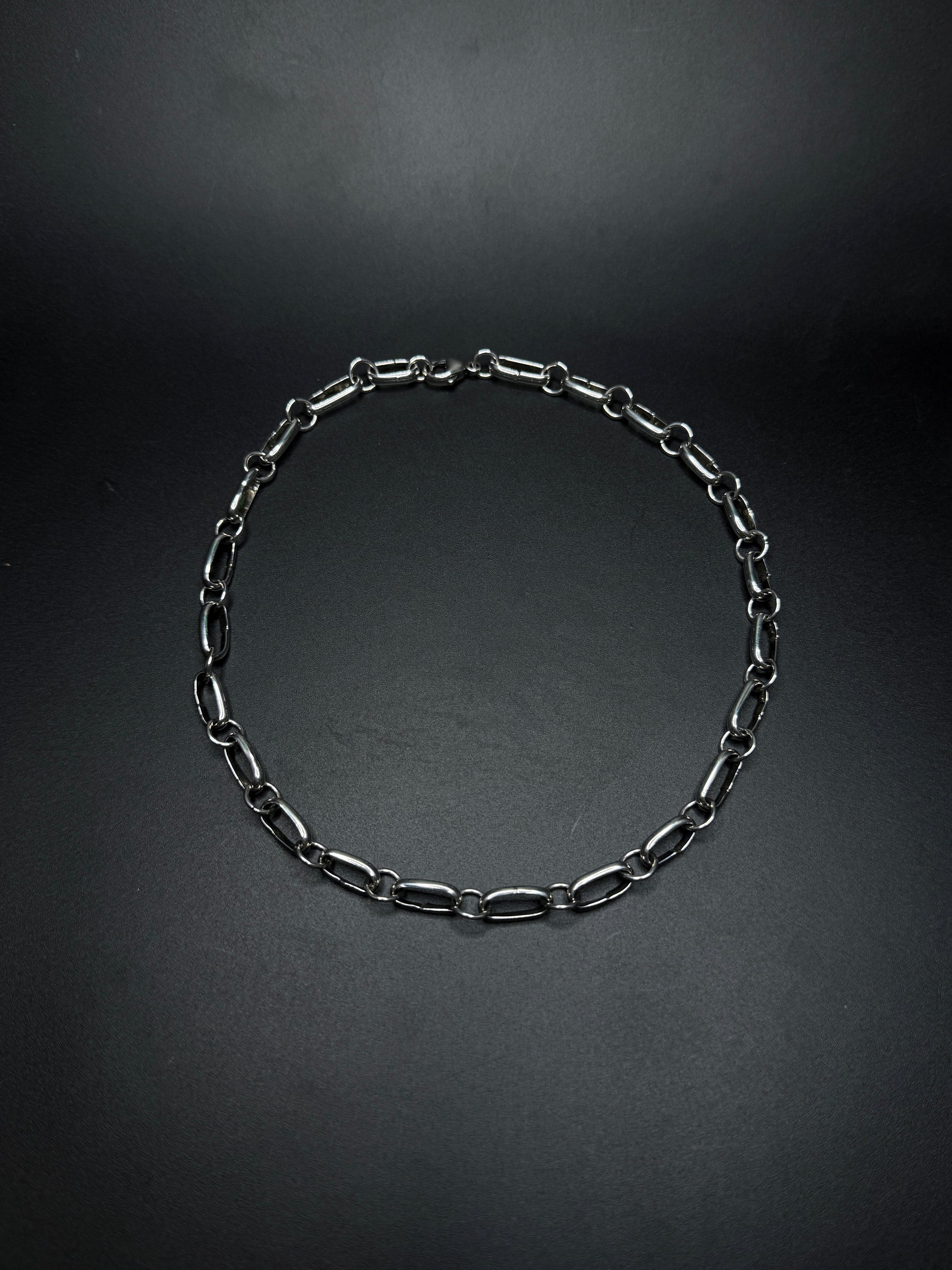 Black chain necklace on a dark gray background